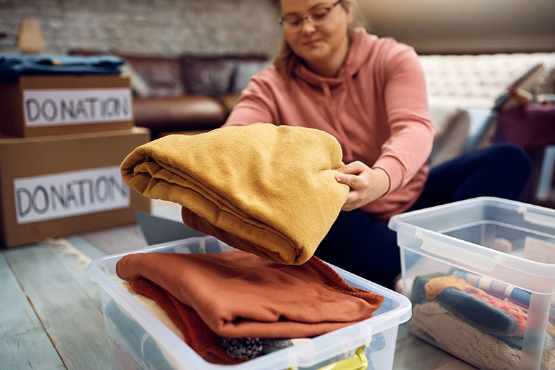 Close-up of woman sorting clothes while packing donation boxes for charity.